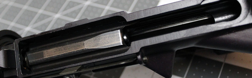 detail of the underside of an AR-15 bolt carrier, with rear of firing pin visible